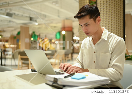 Millennial businessman using laptop and working with financial document in modern office lounge 115501878