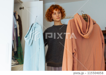 Teenager girl looking at clothes in wardrobe 115504858