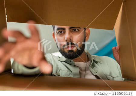 Happy Indian man shopper unpacking cardboard box delivery parcel online shopping purchase at home 115506117