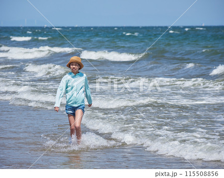 夏の海の海岸のビーチで海遊びする一人の小学生の女の子の様子 115508856