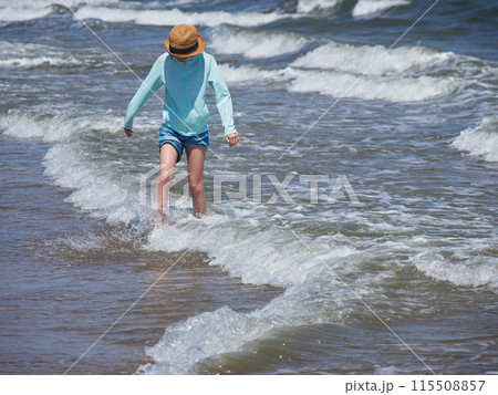 夏の海の海岸のビーチで海遊びする一人の小学生の女の子の様子 115508857
