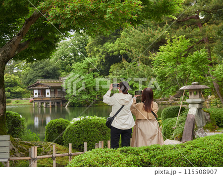初夏の新緑の兼六園で記念写真を撮影する若い女性観光客の姿 初夏の新緑の兼六園で記念写真を撮影する若い女性観光客の姿 115508907