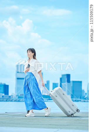 スーツケースを手に歩く若い女性 115509179