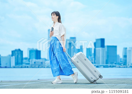 スーツケースを手に歩く若い女性 スーツケースを手に歩く若い女性 115509181