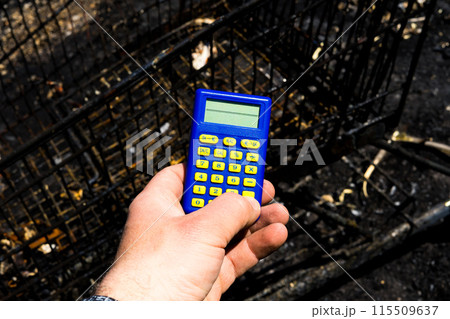 Blue calculator in dark soil, burnt ground after the fire 115509637