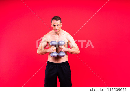 Adult muscular man smiling and screaming while working out hard with dumbbells. 115509651