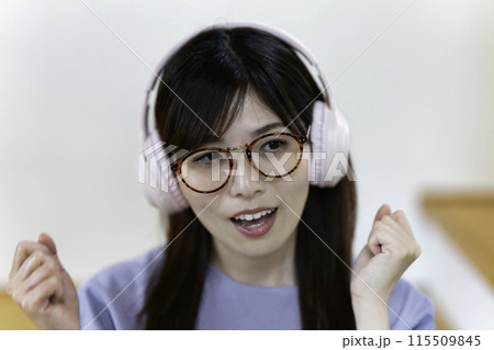 ヘッドホンで音楽を聴く眼鏡をかけた女性 115509845
