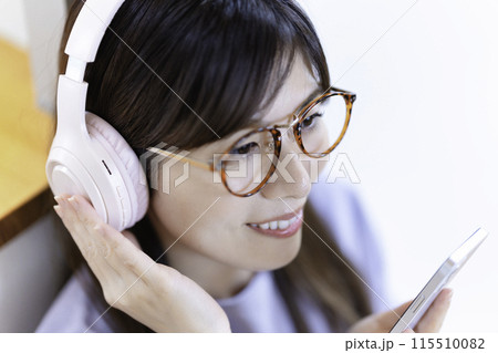 ヘッドホンでスマホ音楽を聴く眼鏡をかけた女性 115510082