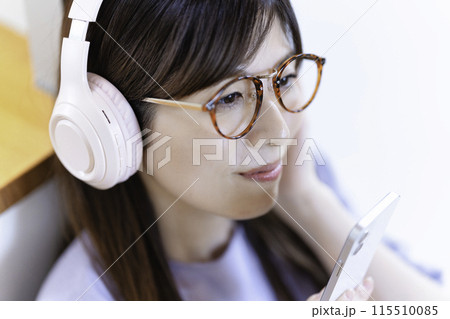 ヘッドホンでスマホ音楽を聴く眼鏡をかけた女性 115510085