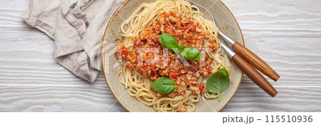 Plate of spaghetti bolognese with basil on wooden table Plate of spaghetti bolognese with basil on wooden table 115510936