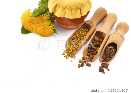A jar of honey with fabric lid, pollen granules, beebread, and dandelion flowers 115511107