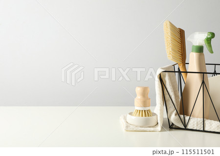 Towel, brushes and bottle of detergent in basket on gray background, space for text Towel, brushes and bottle of detergent in basket on gray background, space for text 115511501