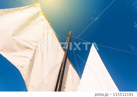 White sails close-up on a background of blue sky with clouds. Yachting and sailing. Summer vacation and travel at sea 115512191