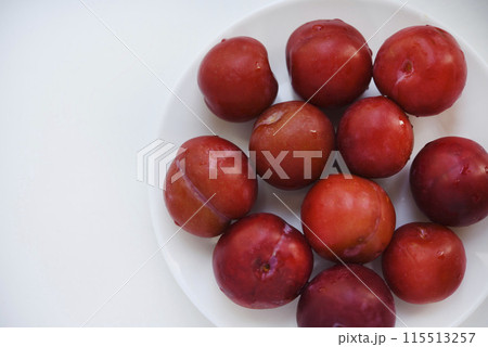 Red plums on a white background.  Plums on a plate. Washed fruits. 115513257