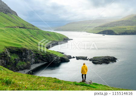 Lonely tourist standing on edge of the cliff on Vagar island 115514616