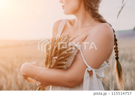 Woman wheat field. Agronomist, Woman farmer check golden ripe barley spikes in cultivated field. A woman is holding a bunch of wheat in her arms. 115514757