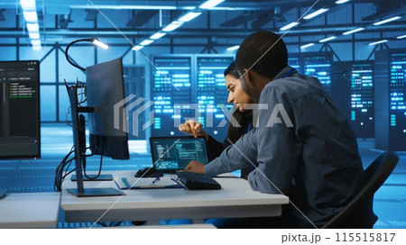 Multiethnic coworkers doing system analysis of server farm supercomputers using tablet. Diverse team of engineers looking at parameters in data center housing storage infrastructure 115515817