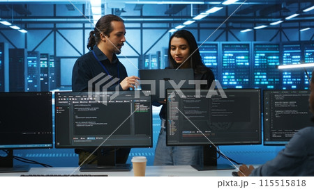 Programmer and supervisor in server room looking for equipment misconfigurations, doing brainstorming. Multiracial colleagues checking data center gear bottlenecks leading to glitches 115515818