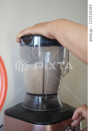 Person making smoothie in blender with food and liquid in kitchen appliance Person making smoothie in blender with food and liquid in kitchen appliance 115518163