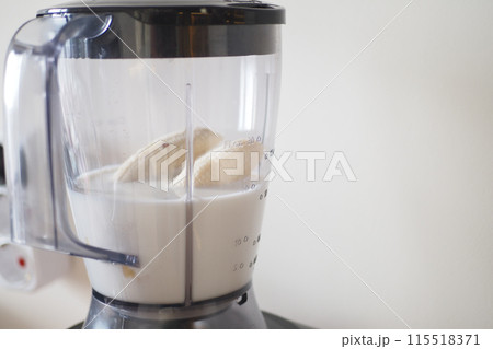 Person making smoothie in blender with food and liquid in kitchen appliance 115518371