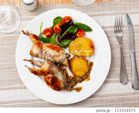 Fried quail served with potatoes and salad 115519373