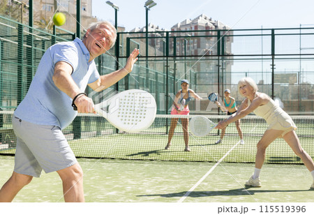 Mature sporty man playing padel game in court on sunny day Mature sporty man playing padel game in court on sunny day 115519396