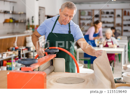 male potter works with machine clay press roller male potter works with machine clay press roller 115519640