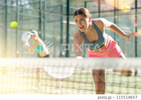 Young sporty woman playing padel game in court on sunny day 115519657
