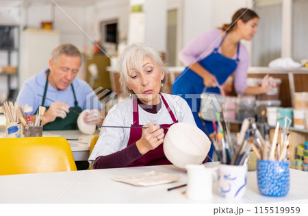 Mature woman painting clay ceramic at art studio Mature woman painting clay ceramic at art studio 115519959