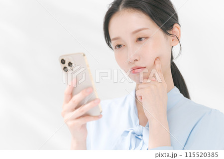 スマホを見て困る表情の女性 115520385