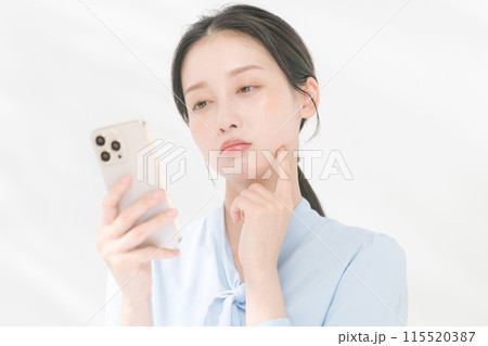 スマホを見て困る表情の女性 115520387