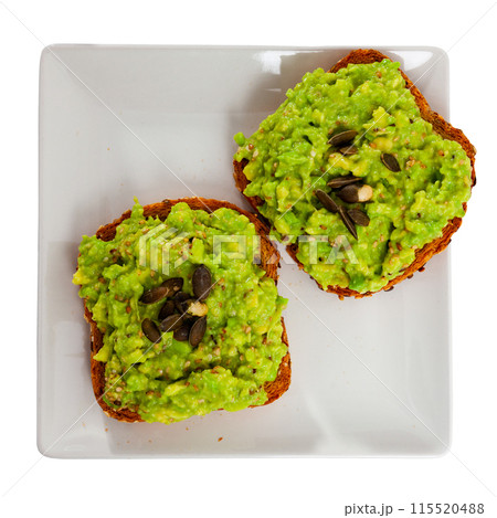 Two whole grain toasts with guacamole and pumpkin seeds 115520488