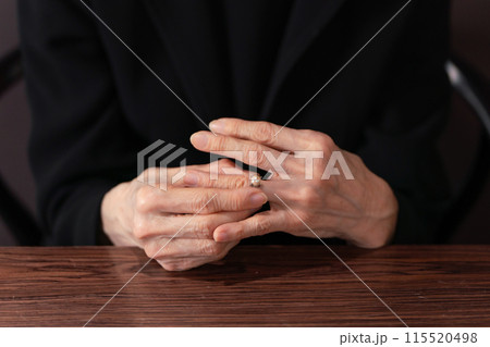 指輪を外す喪服の女性 115520498