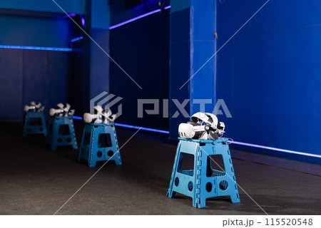 VR headsets and controllers in virtual reality gaming room 115520548
