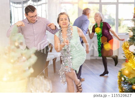 Middle-aged man and elderly woman are dancing contemporary twist in couple in Christmas atmosphere 115520627