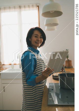 レシピ動画をタブレットで見ながら料理をする40代主婦 115521786