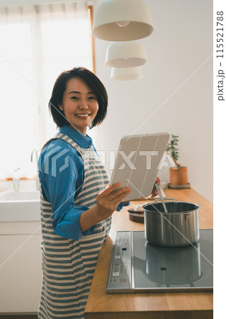 レシピ動画をタブレットで見ながら料理をする40代女性 レシピ動画をタブレットで見ながら料理をする40代女性 115521788