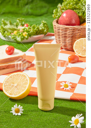 In the middle of photo frame, an unlabeled tube placed on yellow green grass in front, Behind it is an orange carpet containing some fresh ingredient for meal. Front view, space for text In the middle of photo frame, an unlabeled tube placed on yellow green grass in front, Behind it is an orange carpet containing some fresh ingredient for meal. Front view, space for text 115521969