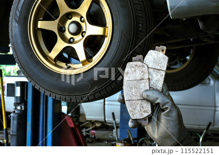 Car brake system maintenance concept , mechanic hand holding a car brake pad in car repair garage 115522151