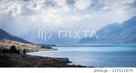 Alpine landscape scenery with azure lake, patches of sunlight and thick clouds of approaching storm Alpine landscape scenery with azure lake, patches of sunlight and thick clouds of approaching storm 115522874
