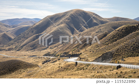 Curvy road leading through high mountain pass with autumn colors in Lindis Pass, New Zealand 115522890