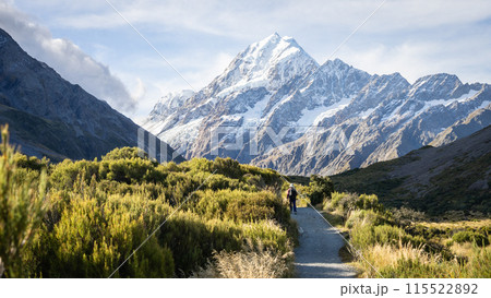 Tourist on the trail in beautiful alpine valley facing huge snowy mountain, Mt Cook, New Zealand Tourist on the trail in beautiful alpine valley facing huge snowy mountain, Mt Cook, New Zealand 115522892