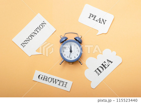 A clock sits on a table with a bunch of paper with words like growth, plan A clock sits on a table with a bunch of paper with words like growth, plan 115523440