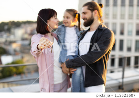 Happy family holding keys to their new home on rooftop Happy family holding keys to their new home on rooftop 115523607