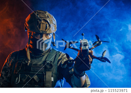 A soldier is depicted holding a drone while wearing stealth gear for military operations 115523971