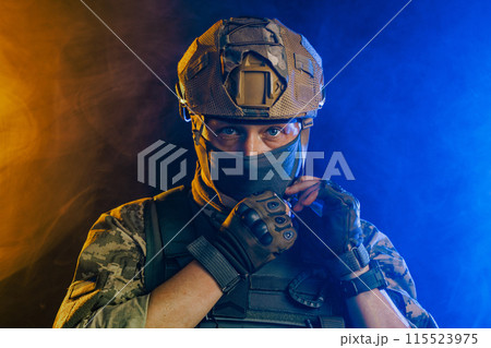 Portrait of a Ukrainian tactical soldier in combat gear on a bright orange and blue background, Military conflict 115523975