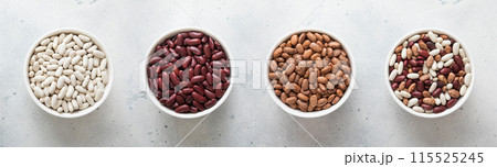 Ceramic bowls with red and white and variegated and mixed raw dry beans on kitchen table. 115525245