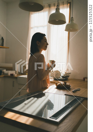 キッチンでマグカップを持った40代主婦 キッチンでマグカップを持った40代主婦 115525322