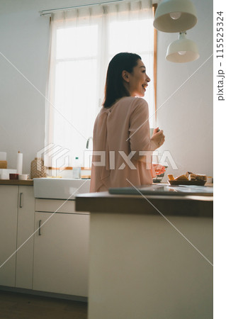 キッチンでマグカップを持った40代主婦 キッチンでマグカップを持った40代主婦 115525324