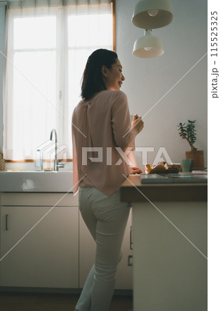 キッチンでマグカップを持った40代主婦 115525325